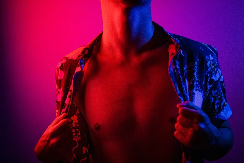 Shirtless man under colourful lighting representing gay men sexual wellness and confidence