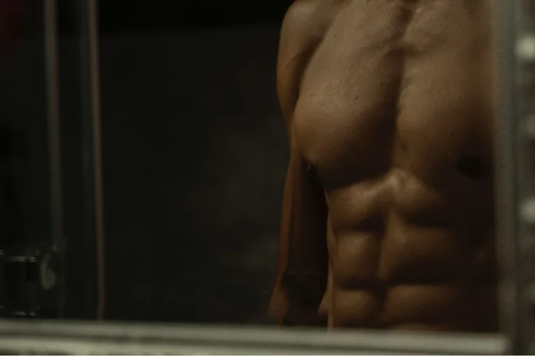 Shirtless man in mirror representing body confidence and self-pleasure for gay men