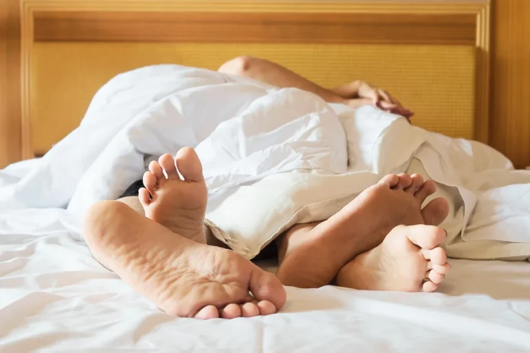 Couple's feet peeking out from under the blanket in bed, a cozy couple moment
